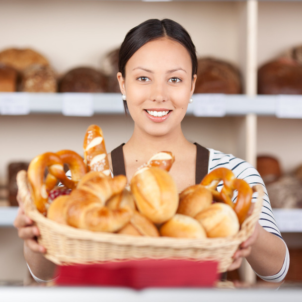 smiling saleswoman holding breadbasket in bakery - Foto, afbeelding