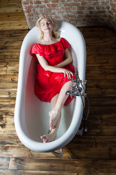Blondi märkä mekko istuu kylpyhuoneessa vedellä
 - Valokuva, kuva