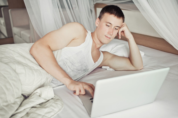 Man lying in bed with his laptop - Photo, Image