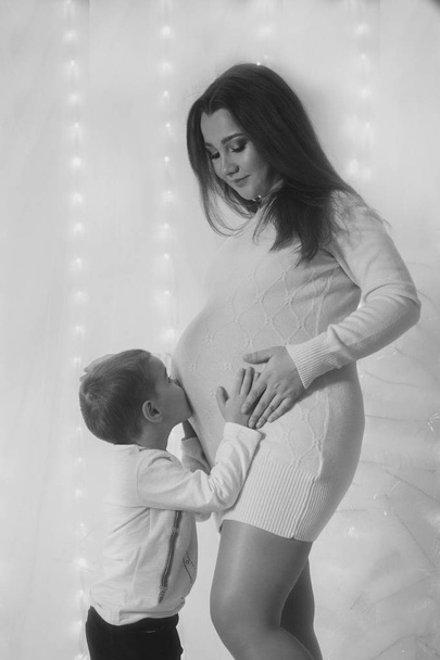 Gelukkig kind meisje knuffelen zwangere moeders buik, zwangerschap en nieuw leven concept - Foto, afbeelding