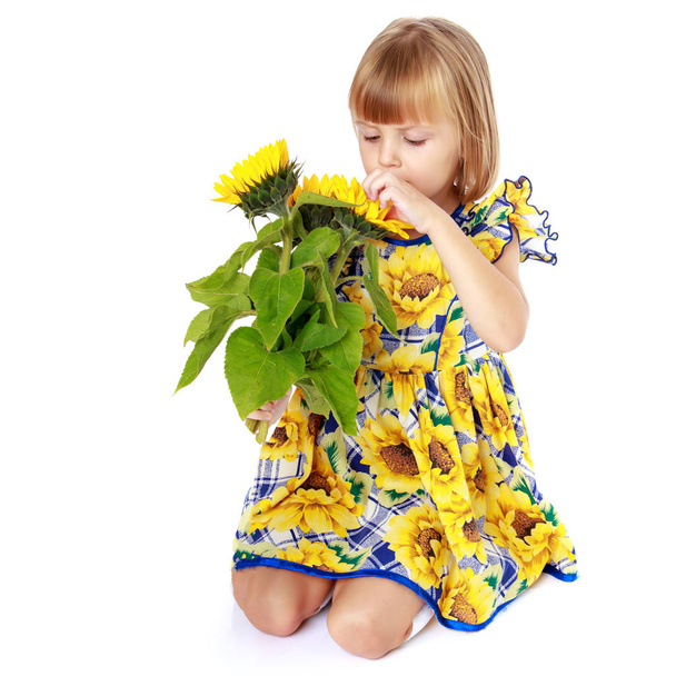 Little girl with flowers of sunflower. - Valokuva, kuva