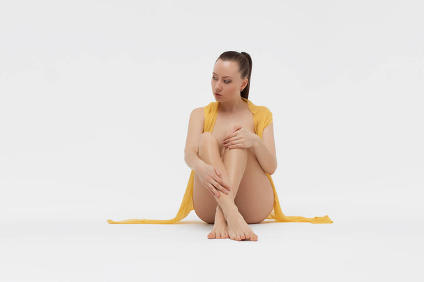 Γυμνή νεαρή γυναίκα κάθεται στο πάτωμα - Φωτογραφία, εικόνα