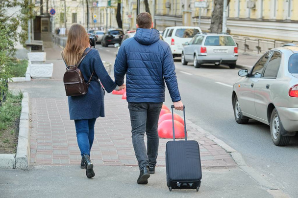 Tourists young couple walking around the city with camera suitcase, view from the back, youth traveling, winter spring season. - Foto, afbeelding