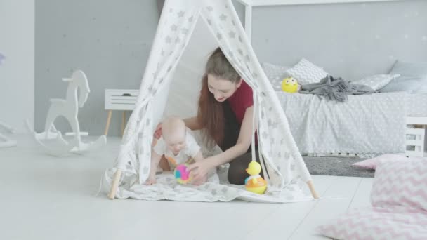Alegre madre jugando con el bebé en cabaña para niños
 - Metraje, vídeo