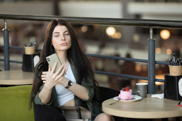 Porträt einer glücklichen Frau, die in einem Café drinnen am Tisch sitzt und ein Stück Kuchen isst und Kaffee trinkt - Foto, Bild