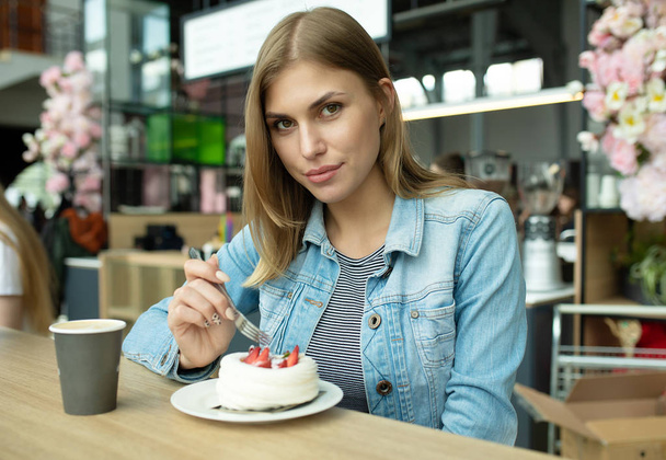 Muhteşem gülümseyen genç kadın pasta yiyor ve kafeteryada kahve içiyor.  - Fotoğraf, Görsel