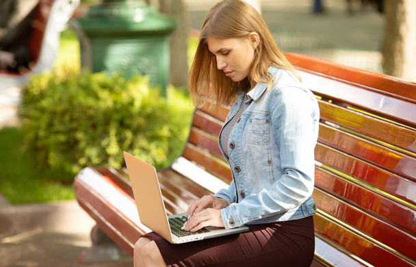 Jovem empresária sentada no parque e trabalhando com laptop. Negócios, educação, conceito de estilo de vida
.  - Foto, Imagem