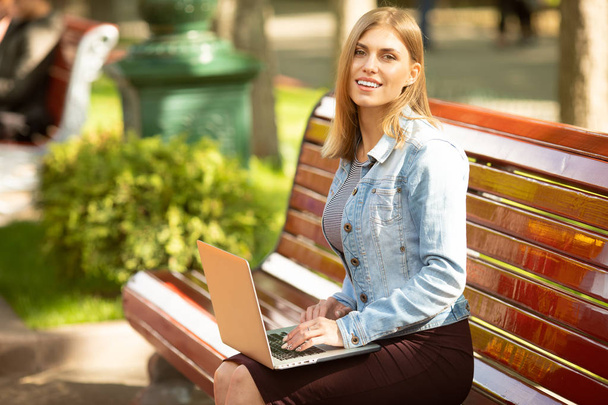 Young businesswoman sitting in the park and working with laptop. Business, education, lifestyle concept.  - Foto, Imagem