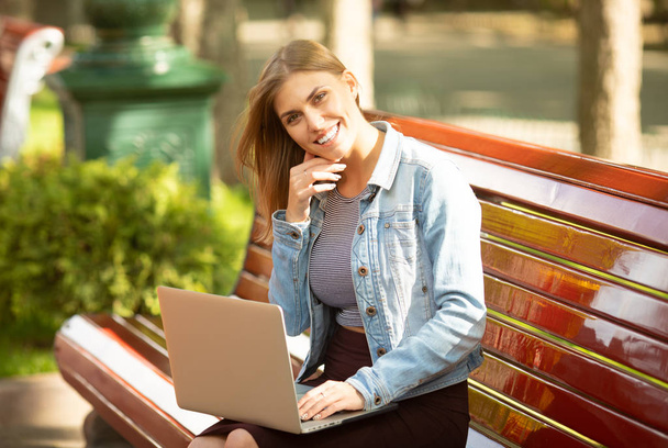 Young businesswoman sitting in the park and working with laptop. Business, education, lifestyle concept.  - Foto, imagen