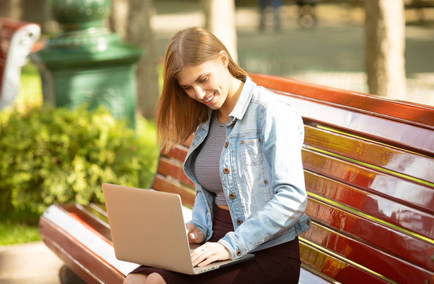 Young businesswoman sitting in the park and working with laptop. Business, education, lifestyle concept.  - Фото, изображение