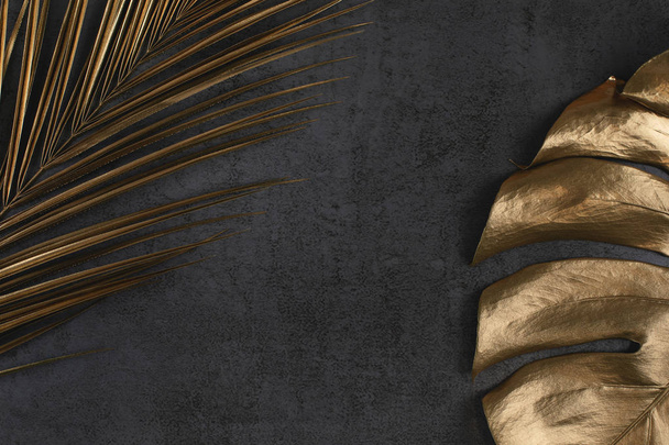 golden palm and monstera leaves on dark grey background - Foto, Imagen