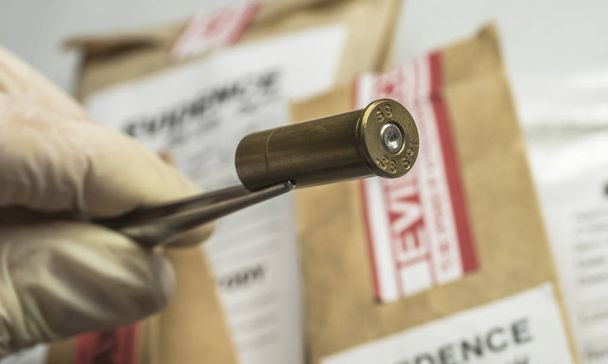 Laboratório Criminalista, Oficial de Polícia Científica detém pontas de bala com pinças para análise balística, imagem conceitual
 - Foto, Imagem