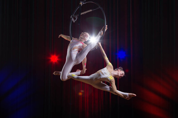Circus actress acrobat performance. Two girls perform acrobatic elements in the air ring. - Photo, Image