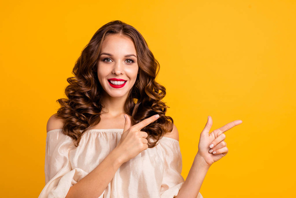 Close-up portrait of her she nice attractive lovely cheerful cheery positive wavy-haired lady pointing two forefingers aside ad new novelty isolated over bright vivid shine yellow background - Foto, imagen
