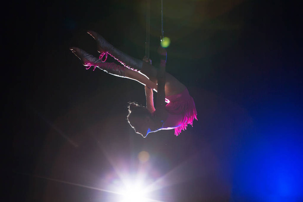 サーカスアーティストアクロバットパフォーマンス。女の子は空気中のアクロバット要素を実行します。ステージ上のサーカス体操選手 - 写真・画像