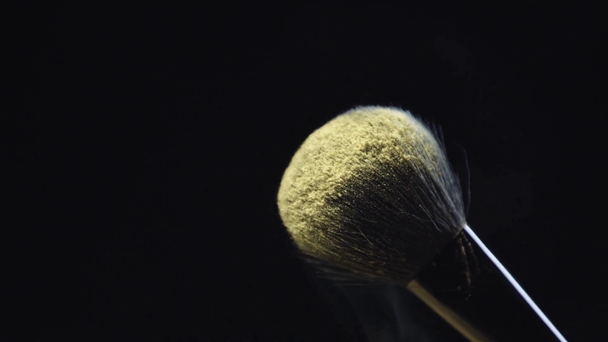 slow motion shoot of yellow holi paint scattering from cosmetic brush on black background - Footage, Video