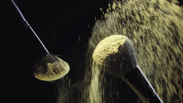 slow motion shoot of two cosmetic brushes touching and scattering yellow holi paint - Filmagem, Vídeo
