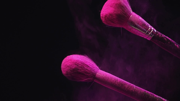 slow motion shoot of two cosmetic brushes hitting and making splashes of pink holi paint - 映像、動画