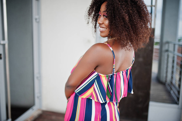 Fashionable african american woman in pink striped jumpsuit, wit - Foto, Imagen
