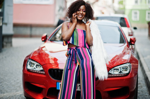 Fashionable african american woman in pink striped jumpsuit with - Foto, imagen