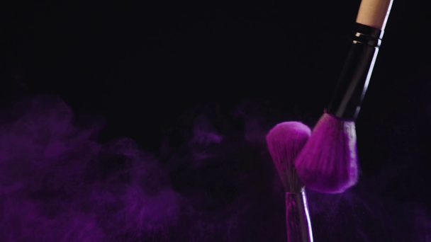 slow motion shoot of two cosmetic brushes rubbing and scattering colorful purple holi paint - Footage, Video
