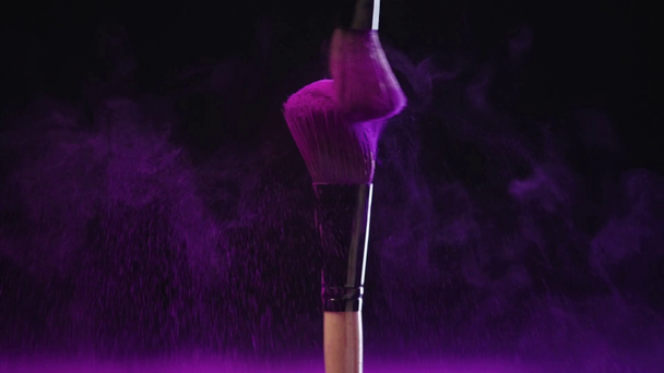 slow motion of two cosmetic brushes rubbing and scattering colorful purple holi powder - Footage, Video