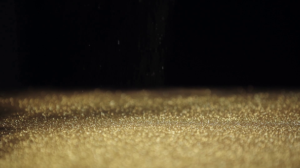 slow motion shoot of shiny golden glitter falling down on black background - Footage, Video