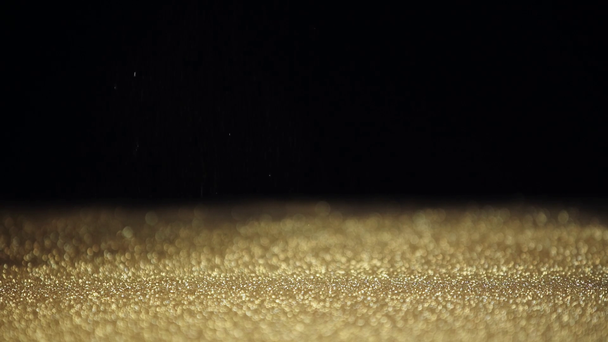 slow motion shoot of shiny golden sparkles falling down on black background - Footage, Video