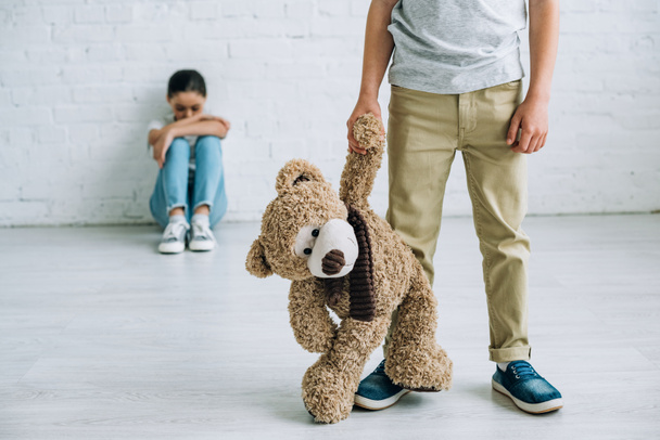 partial view of boy with teddy bear and his sister sitting on floor - Фото, изображение