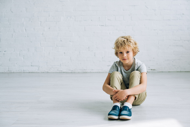 cute little boy sitting on floor with gently smile and looking at camera - Foto, immagini