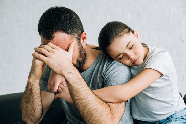 sad kid embracing stressed father in living room - Fotografie, Obrázek