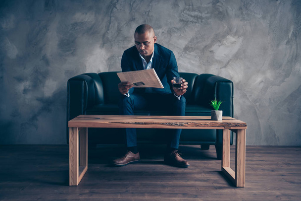 Portrait of his he nice stylish classy chic imposing elegant attractive guy professional top manager company banker sitting on couch reading paper at workplace station gray concrete wall - Foto, Imagem