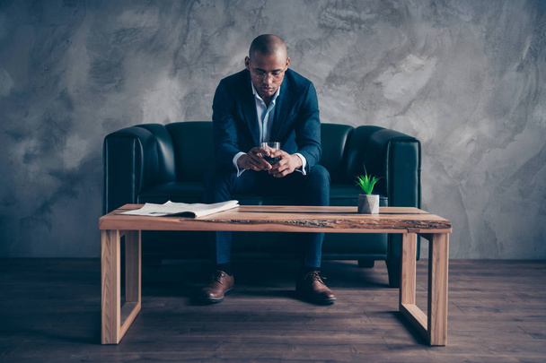 Portrait of his he nice stylish trendy classy imposing elegant attractive guy top manager company director sitting on couch drinking beverage at workplace station gray concrete wall - Фото, изображение