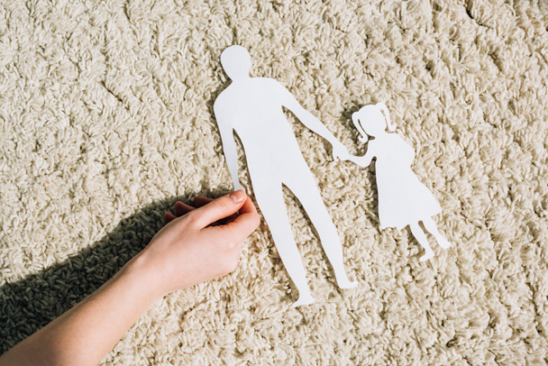 Teilansicht einer Frau mit Papierfiguren auf Teppich - Foto, Bild