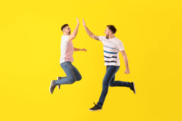 Jumping young men on color background - Foto, Bild
