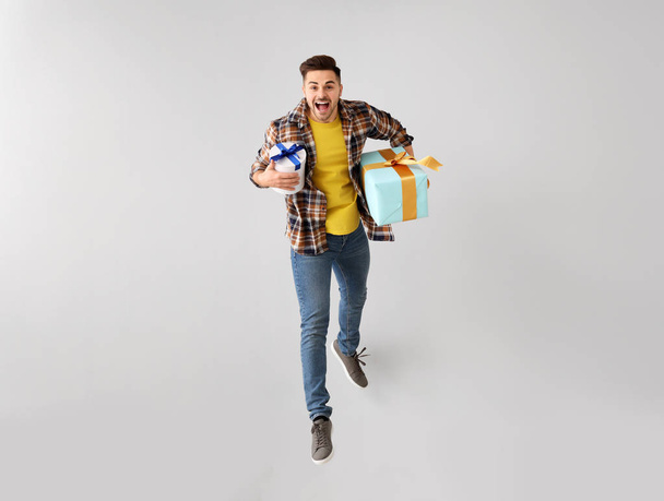 Hafif arka planda hediye kutuları ile atlama genç adam - Fotoğraf, Görsel
