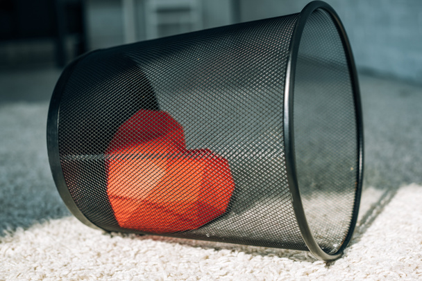 red heart in black trash can on carpet - Foto, Bild
