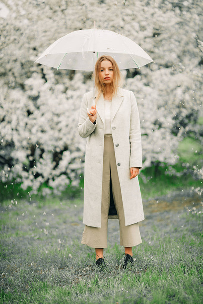 Une femme blonde se détend avec un parapluie dans ses mains parmi les spri
 - Photo, image