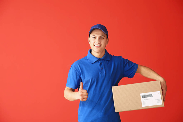 Uomo di consegna con scatola che mostra pollice su sfondo a colori
 - Foto, immagini