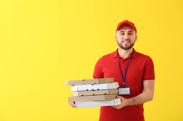 Handsome delivery man with pizza boxes on color background - 写真・画像