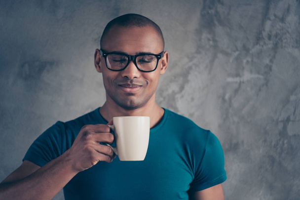 Close up photo amazing he him his dark skin macho handsome hand arm hold raise hot beverage have free minute delicious break office working day wear specs casual blue t-shirt isolated grey background - Fotó, kép