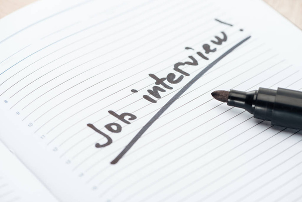 close up of job interview lettering on white paper near black marker - Foto, Imagem