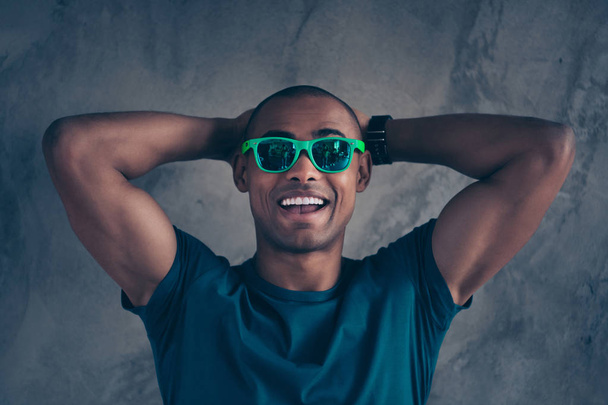 Close up photo amazing funky he him his dark skin macho hot modern look trend hold hands arms behind head great day mood weather excited wear specs casual blue t-shirt isolated grey background - Foto, afbeelding
