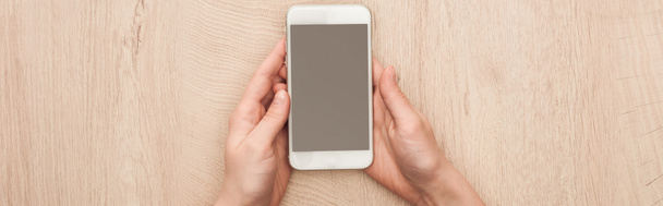 panoramatický záběr ženy držící smartphone s prázdnou obrazovkou v rukou - Fotografie, Obrázek