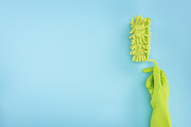 cropped view of cleaner in green rubber glove holding sponge on blue background - Φωτογραφία, εικόνα