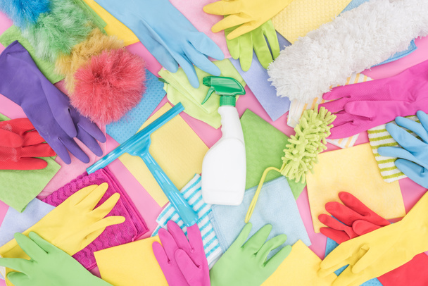 top view of messy scattered multicolored cleaning supplies on pink background - Zdjęcie, obraz
