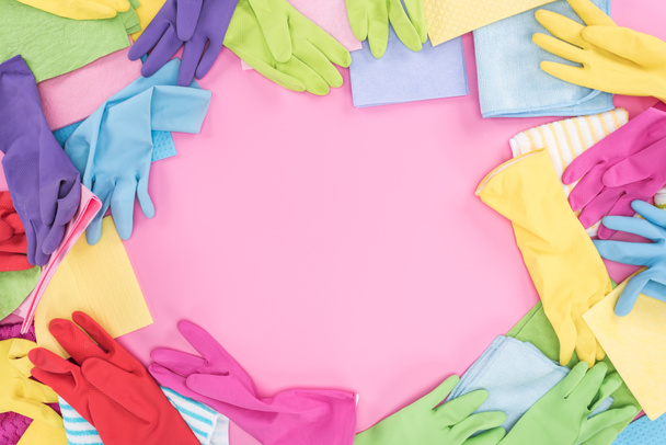 Draufsicht auf chaotisch verstreute bunte Lumpen und Gummihandschuhe auf rosa Hintergrund mit Kopierraum - Foto, Bild