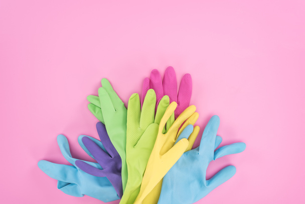 top view of colorful rubber gloves on pink background  - Фото, изображение