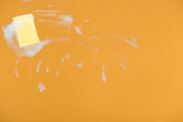 esponja amarela com espuma no fundo laranja
 - Foto, Imagem