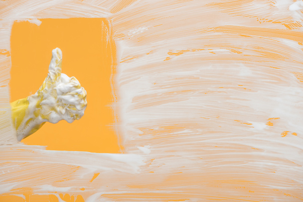 Ausgeschnittene Ansicht eines Reinigers im gelben Gummihandschuh mit Schaumstoff, der den Daumen nach oben zeigt - Foto, Bild